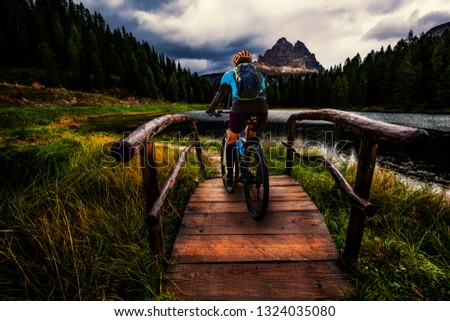 Woman cycling in majestic mountains landscape of Antorno Lake, Lago Antorno in Misurina near Cortina d’Ampezzo. , Italy Europe.