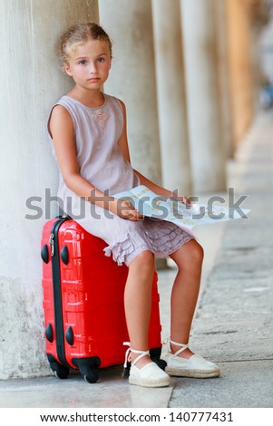 Young traveler sitting on suitcase with city plan, Venice, Italy.