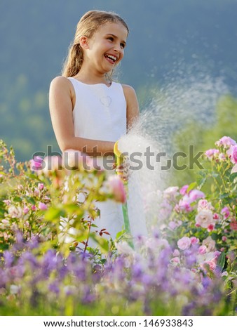 Summer fun,  garden, watering - beautiful  girl watering roses with garden hose
