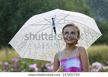 Summer rain - happy girl with an umbrella in the rain