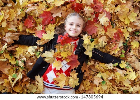 Autumn fun - lovely girl has a fun in autumn leaves, happy child