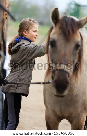 Horse and lovely equestrian girl - young girl takes care of the horse