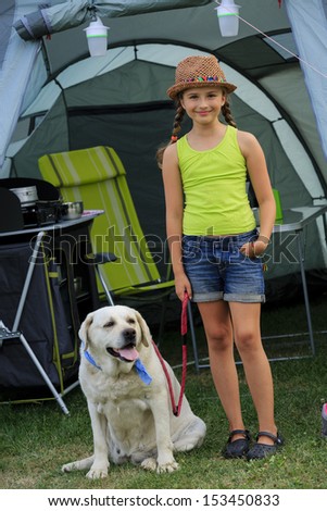 Summer in the tent - young girl playing with dog on the camping