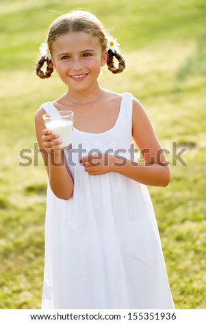 Healthy kid - lovely girl drinking fresh milk outdoors
