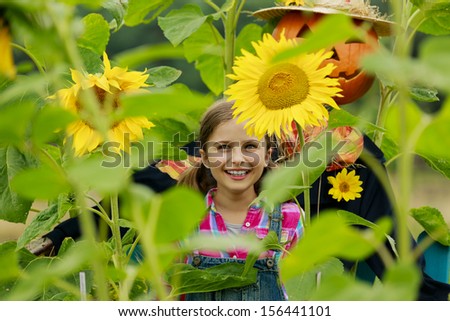 Autumn harvest - Scarecrow and happy girl  in the garden