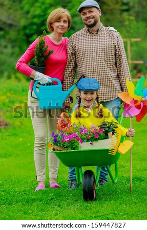 Gardening - happy family with wheelbarrow working in the garden