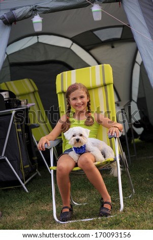 Summer in the tent - young girl playing with dog on the camping