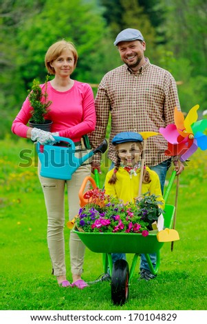 Gardening, planting - happy family with wheelbarrow working in the garden