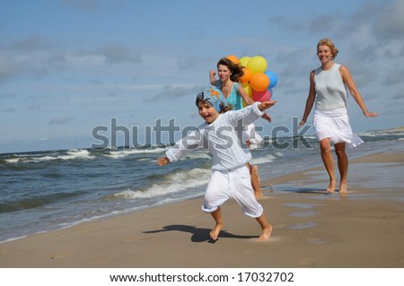 Happy mother running with daughters on the beach