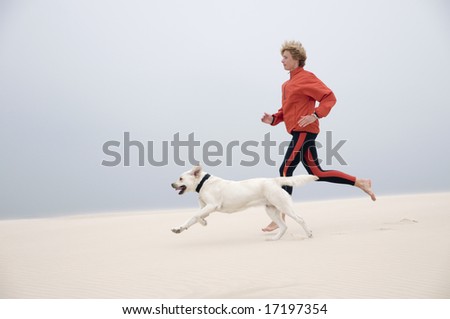 Woman running with dog on the dune