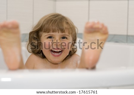 Happy little girl playing in bath