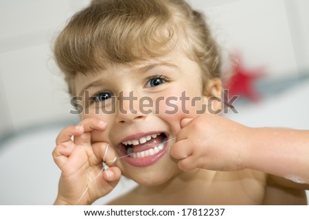 Cute girl cleaning teeth by floss in bath