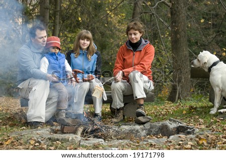 Happy family with dog near campfire