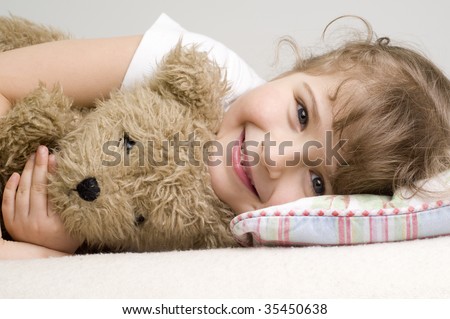 Little girl with teddy bear on sofa