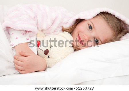 Cute girl in bed hugging no-name teddy bear