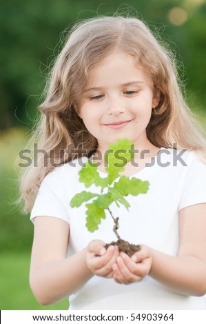 Little girl and young plant of a oak