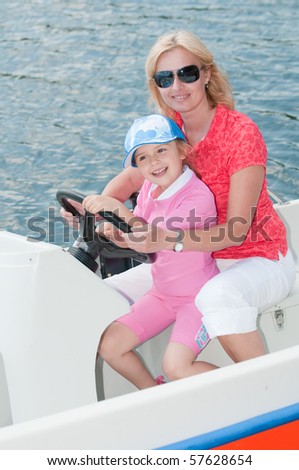 Little girl with mother driving a motor boat
