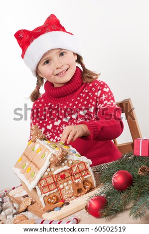 Little girl decorating oneself made Christmas cookies house