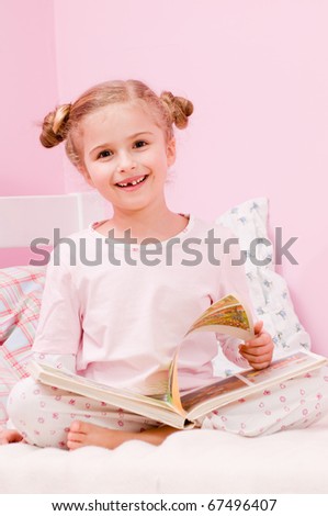 Story time - little girl reading book in bed