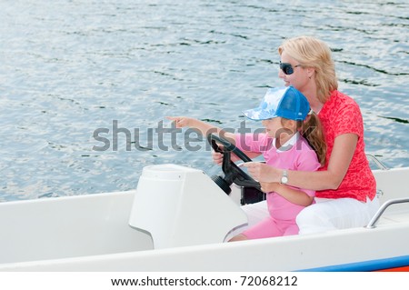 Summer vacation - little girl with mother driving a motor boat