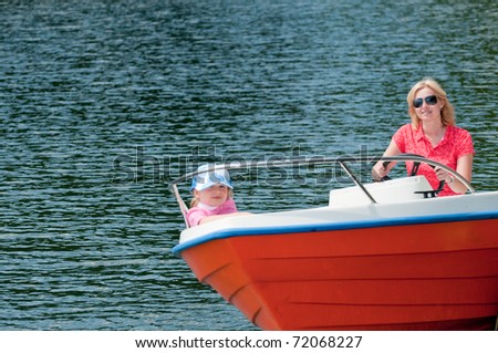 Summer vacation - little girl with mother driving a motor boat
