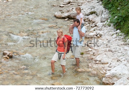 Mountain trek - family crossing through mountain river