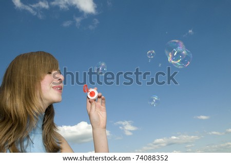 Soap bubbles - young girl blowing bubbles - space for text