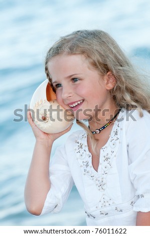Summer vacation - Listening to the sea - beautiful girl with shell at the beach