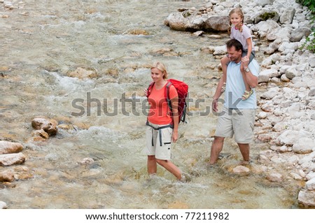 Mountain trek - family crossing through mountain river