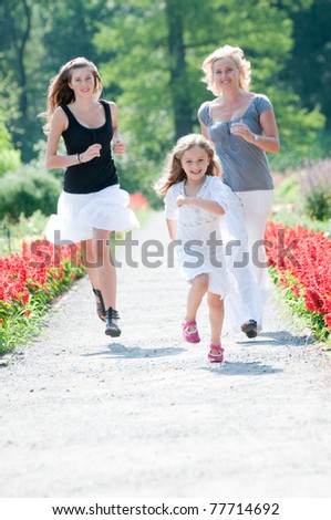 Happy together - mother with daughters running in the park