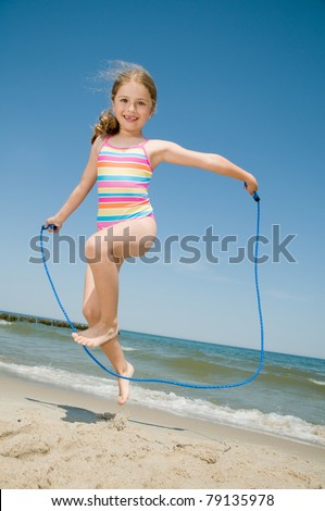 Summer vacation - little girl with skipping rope on the beach