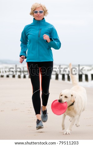 Woman running with dog on the beach