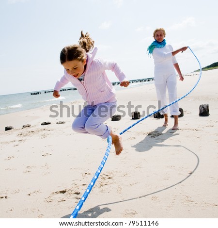 Summer vacation - family  playing with skipping rope on the beach