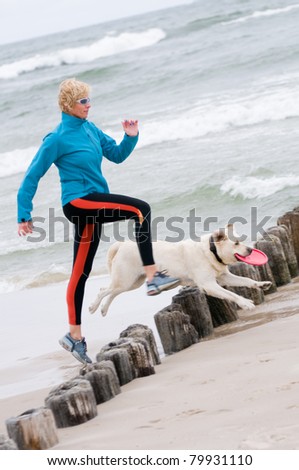 Healthy lifestyle - woman running with dog on the beach