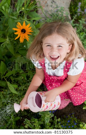 Gardening - happy girl watering flowers in the garden