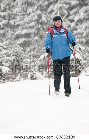 Winter Nordic Walking - female trekking in winter mountains