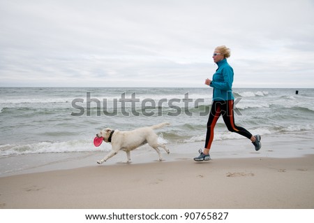 Healthy lifestyle - woman running with dog on the beach
