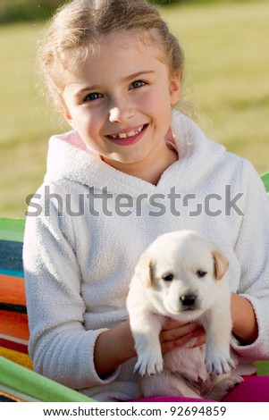 Happy childhood - little girl with cute Labrador puppy in hammock