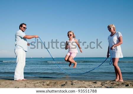 Summer vacation - family playing with skipping rope on the beach