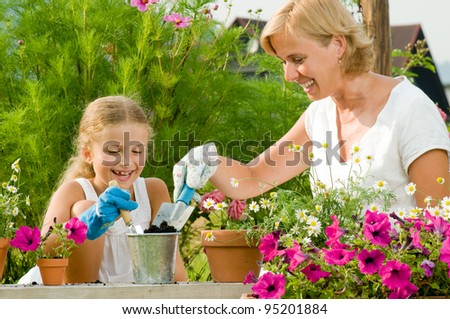 Gardening, planting - mother with daughter planting flowers into the flowerpot