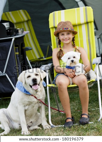 Summer in the tent - young girl playing with dogs on the camping