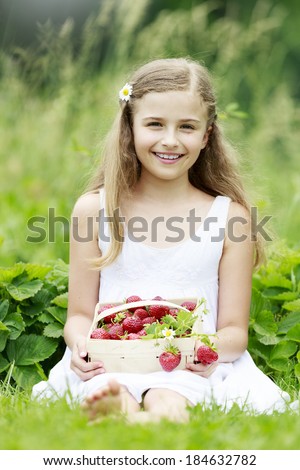 Strawberry, fruit garden - young girl with picked strawberries in the garden