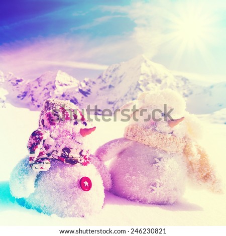 Winter, snow, sun and fun, winter vacation, Christmas - happy snowman friends and snowy mountains in background, filtered