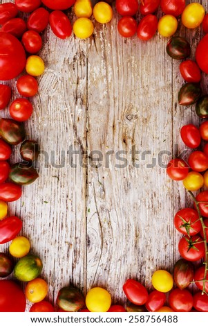 Frame of tomatoes family varieties over a rustic wooden background with copyspace