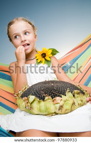 Rest in the garden - Girl in hammock with the seeds of the sunflower