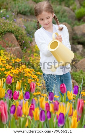 Spring garden - lovely girl watering flowers in the garden