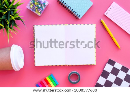 Student\'s desk. Notebook, stationery, coffee cup on pink background top view mock up