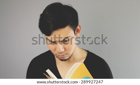 A man seriously reading his yellow book.