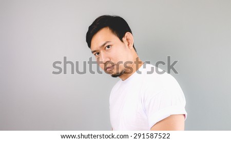A man turn his face to the camera. An asian man with white t-shirt and grey background.