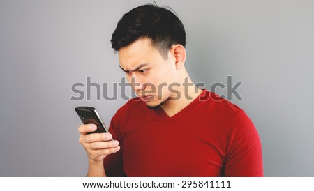 Asian man in red T-shirt is feeling bad with the smartphone.